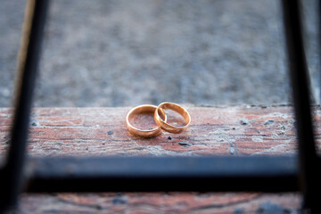 Golden wedding rings resting on wood. Two golden wedding rings placed on weathered wood, showcasing...