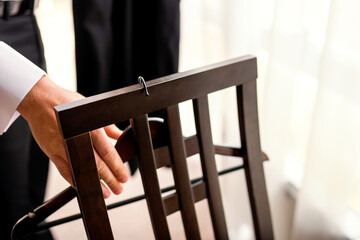 Hand grasping a wooden chair. A hand grips the back of a dark wooden chair in a well-lit indoor...