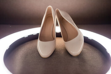 Elegant white heels with lights. Stylish white heels are showcased on a dark surface with...
