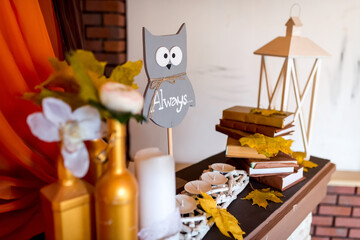Cozy autumn decor for gatherings. A warm and inviting autumn decoration features an owl sign,...