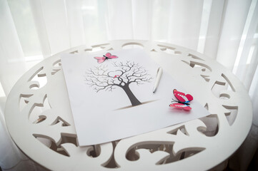 Artistic tree drawing on a table. A detailed tree drawing with butterflies rests on a decorative table by a bright window, highlighting creativity.