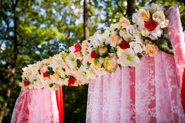 Woodland floral wedding altar. A beautiful wedding altar adorned with pink lace and vibrant flowers, set in a tranquil forest during day.