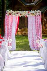 Beautiful outdoor wedding ceremony setup. A decorated arch framed with flowers welcomes guests to a romantic outdoor wedding ceremony taking place in a garden.