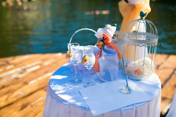 Elegant decoration at a lakeside event. Table adorned with decorative elements, glasses, and...