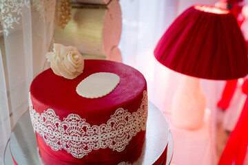 Elegant red lace cake shown. A beautifully crafted red cake adorned with lace and a flower sits...