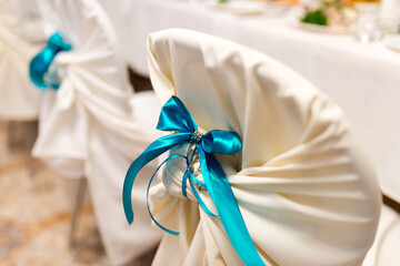 Turquoise ribbon chair decor. Chairs adorned with white covers and turquoise bows set the tone for a special event in a beautifully arranged venue.