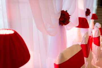 Red and white decor setup. Elegant indoor setup with red and white decor, draped fabric, and floral accents ideal for celebrations.