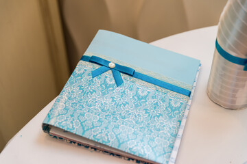 Decorative blue notebook on a table. A beautifully crafted blue notebook with a ribbon sits on a table, showcasing intricate patterns and details.