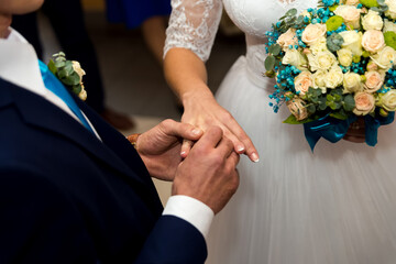 Couple weds in ceremony. A joyful moment as a couple exchanges rings surrounded by flowers, celebrating their love at a wedding venue.