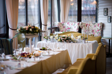 Elegant dining setup for special event. Table beautifully arranged with flowers and candles, perfect for a celebration in a cozy, well-lit venue.
