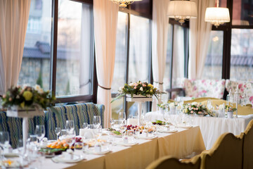 Chic dining for special events. A beautifully arranged dining table featuring floral decorations, glassware, and an array of dishes in a bright venue.