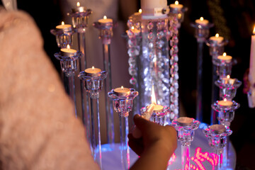 Lighting festive candles. Guests light decorative candles at a joyful gathering, creating an enchanting atmosphere with soft illumination.