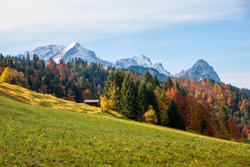 bumpy meadow with hut, colorful forest. Alpspitze, Zugspitze and Waxenstein mountain, bavaria