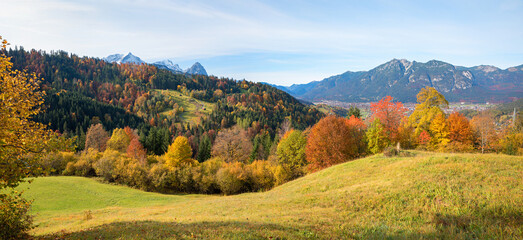 view above meadow and colorful forest to Kramer mountain and Garmisch village