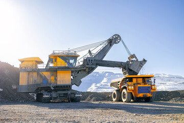 Obraz na płótnie Canvas Banner Open-pit coal mining in winter, heavy machinery excavator loading dump truck