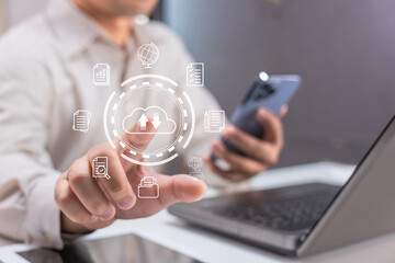 A person uses a smartphone and laptop with digital cloud storage and data icons overlay, symbolizing technology and data management.