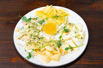 Delicious cheese platter with honey and fresh garnish served on a rustic wooden table