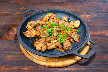Sizzling beef dish with green onions served on a rustic wooden table in a cozy dining setting