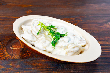 Dumplings served with creamy sauce in a rustic bowl on a wooden table at a cozy restaurant