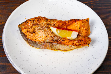 Deliciously grilled salmon with lemon slice served on a speckled plate