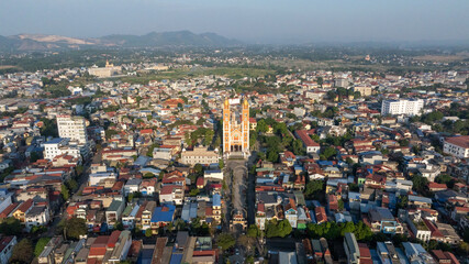 Backlit aerial view of Thai Nguyen's Cathedral, with long shadows and sun glare, showcasing urban life under bright sunlight.