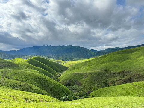 natural and mountain a landscape during the rainy season, showcasing rolling bald mountains with misty air and scattered patches of fresh green grass.