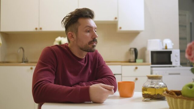 A 30-year-old man enjoys a casual meal and drink in his kitchen, captured in a natural, unposed moment. Authentic and relatable everyday scene perfect for lifestyle and food content