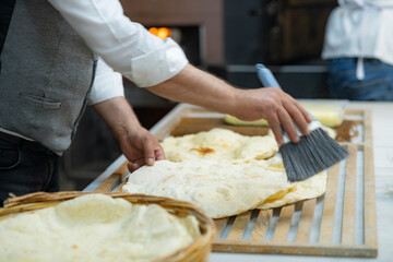 Male hands brushing freshly baked famous flat bread called lavaş in front of a wood burning fire in a traditional bakery in Turkey
