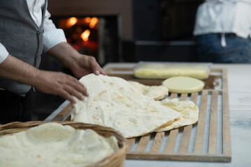 Male hands brushing freshly baked famous flat bread called lavaş in front of a wood burning fire in a traditional bakery in Turkey