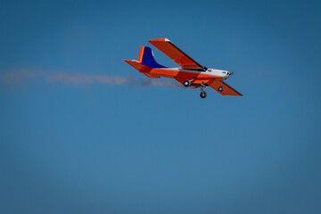 Radio-controlled airplanes perform a show releasing red smoke.