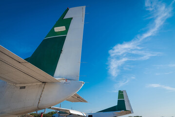 Side view of airplane tail parked on the apron against a blue sky background.