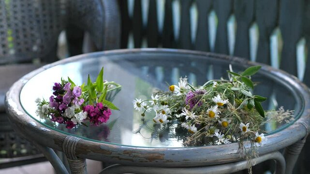Wildflowers and sweet williams resting on glass tabletop in tranquil outdoor setting