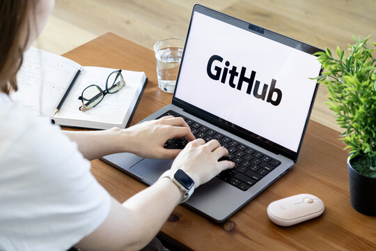 Poznan, Poland - June 15, 2025: GitHub application displayed on laptop screen with person typing, signifying modern software development, coding, and remote work
