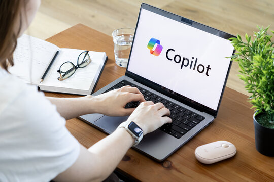 Poznan, Poland - June 15, 2025: Copilot AI assistant software displayed on a modern laptop, with user hands actively typing on keyboard, emphasizing digital productivity and innovation