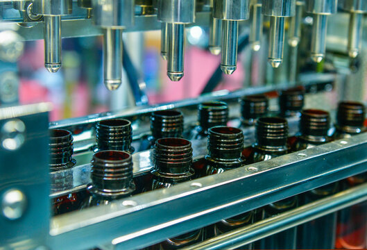 Glass bottles in a conveyor belt on a high quality automatic vertical filling machine. In the factory production line