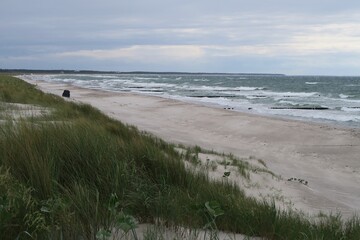 Wellen branden am Strand des Ostseebads Dierhagen auf dem Fischland an einem stürmischen Sommertag. Die Halbinsel gehört zum deutschen Bundesland Mecklenburg-Vorpommern. Oben wächst Strandhafer.