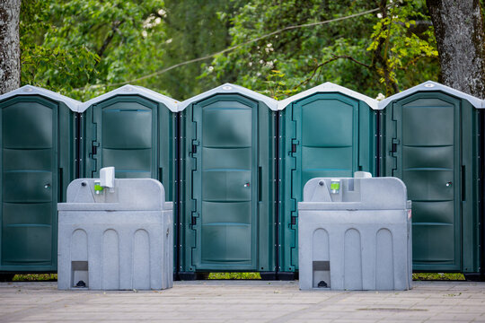 portable outdoor toilets with handwashing stations in public park area mobile sanitation units for events hygiene facilities restroom cabins portable washbasins in green nature environment setup