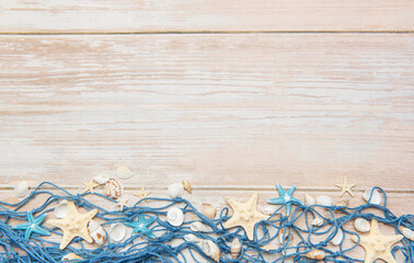 Fishing net with starfishes and seashells creating summer holiday border on wooden planks