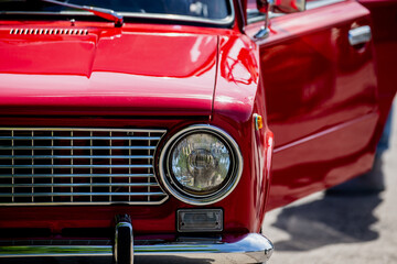 front closeup of red vintage car with open door showing chrome headlight grille classic retro...