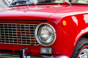 close up front view of red vintage classic car with chrome headlight and grille retro automobile...