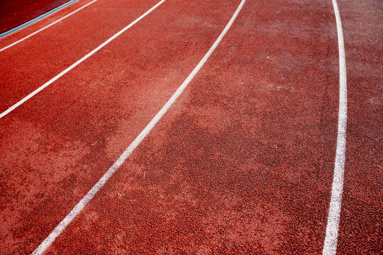 close up view of red running track with white lane markings in outdoor stadium athletics background texture sports competition race surface fitness training jogging path summer sports event field