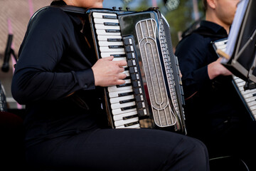musician playing black piano accordion during live performance on stage in black outfit close up of...