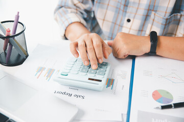 Accountant working on desk using calculator for calculate finance report in office. business...