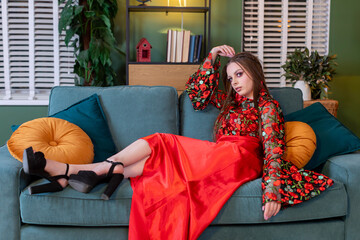 Chic Model in a Beautiful Floral Dress Relaxing Comfortably on a Cozy Couch at Home