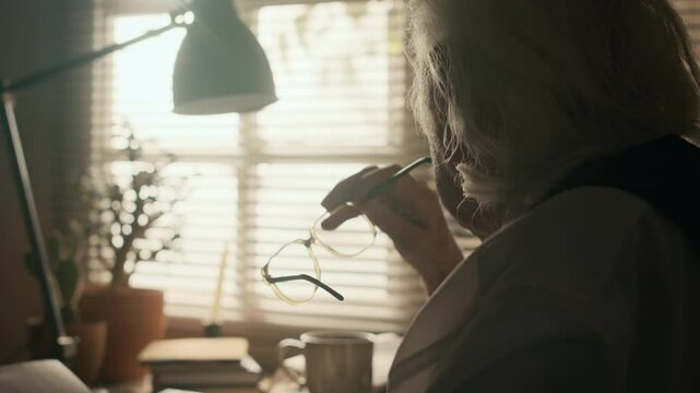 Closeup shot of elderly Caucasian male writer working on new chapter of novel using vintage typewriter sitting in home office by window