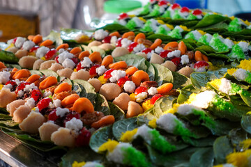 Rows of colorful paan, prepared on betel leaves, at a market stall.