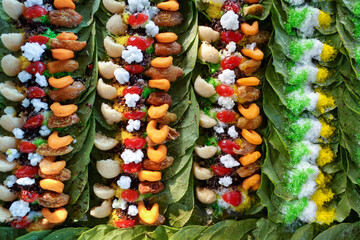 Close-up of colorful paan preparations on betel leaves, arranged in rows, showcasing various sweet treats and spices.
