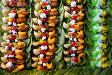 Close-up of colorful paan preparations on betel leaves, arranged in rows, showcasing various sweet treats and spices.