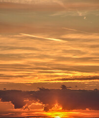Sunset scene with light clouds under a colorful, orange-tinted sky