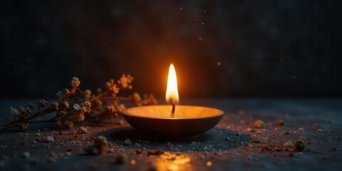 A single flickering candle flame illuminates a dark scene, casting a warm glow on dried flowers and scattered fragments near a rustic wooden candle holder.